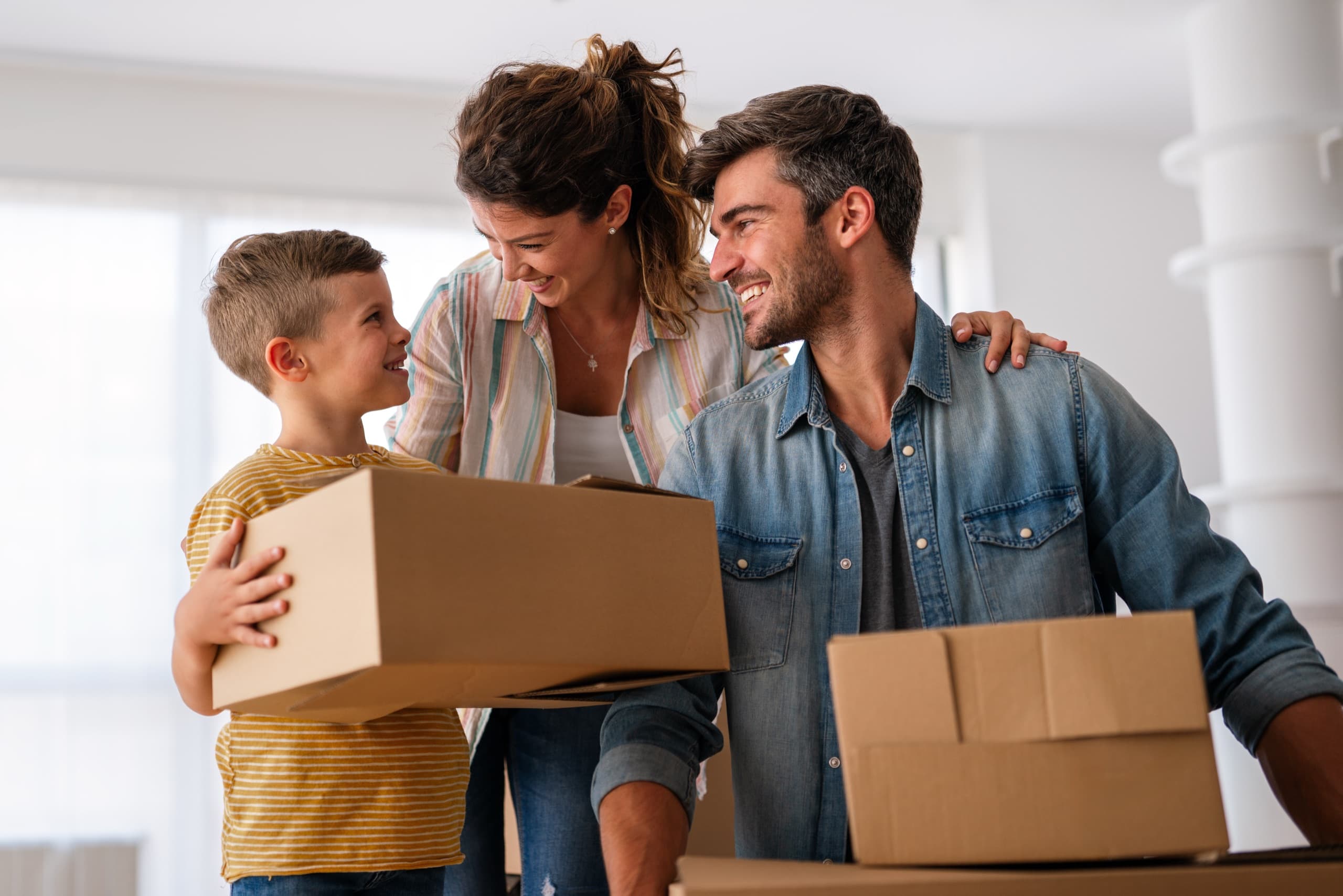 Happy family with cardboard boxes in new house